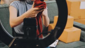 A woman is holding a red sweater in front of a camera video