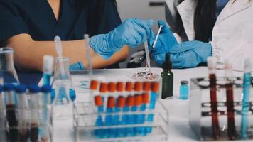 Two people in lab coats and gloves working on a test tube video