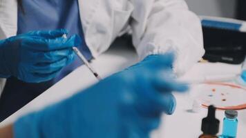 A person in a lab coat is holding a syringe video