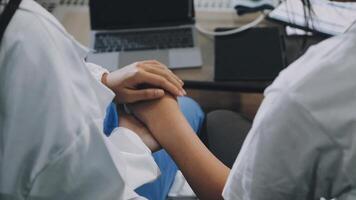 Two doctors holding hands while sitting in front of a laptop video