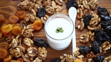 yogurt with nuts, dried apricots and prunes on a wooden table video