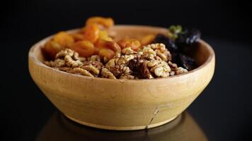 Prunes, dried apricots and nuts in a wooden bowl on a dark background. video