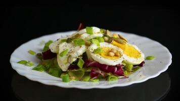 Salad with seeds and vegetables in a plate, isolated on a black background. video