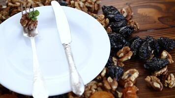 Clean empty plate and Nuts, dried apricots and prunes on a wooden table. video