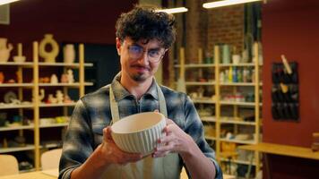 Male potter artist sculptor work with clay art workshop Caucasian positive smiling man guy small business owner creating bowl crockery handmade showing at camera salesman craft pottery ceramics shop video