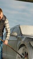 A man using a mop to clean his car at an outdoor self-service car wash video