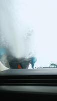 View from inside a car as a car wash worker applies foam to the windshield video