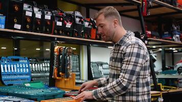 A man carefully inspects a large tool set in a hardware store video