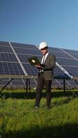 Engineer working on laptop near solar panels in the field video