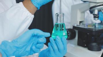 A person in a lab coat holding a green liquid video