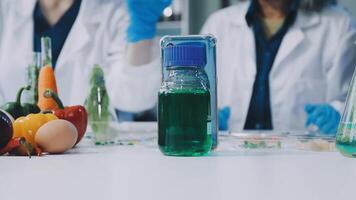 Two people in lab coats are working on a bottle of liquid video