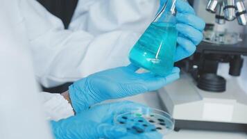 A person in a lab coat holding a blue liquid video