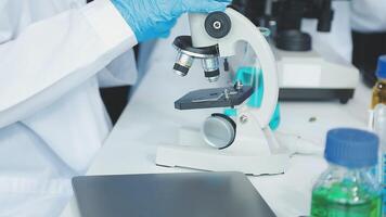 A person in a lab coat is looking through a microscope video