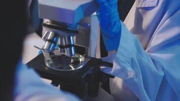 A person in a lab coat is looking through a microscope video