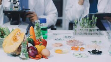 Two people in lab coats are working on a table with food video