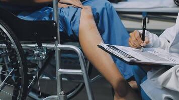 A doctor is writing on a clipboard while a patient sits in a wheelchair video