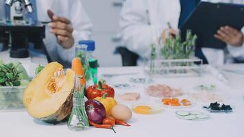 Two people in lab coats are working on a table with vegetables and fruit video