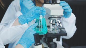 Two people in lab coats holding up a green liquid video
