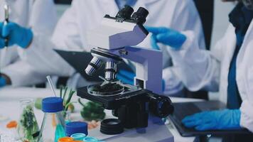 A group of people in lab coats are working on a microscope video
