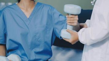 A woman in scrubs is holding a dumbbell video