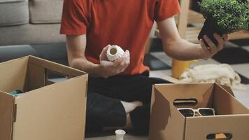 A man sitting on the floor with boxes and plants video