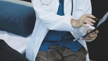 A doctor is holding a clipboard while sitting on a bed video