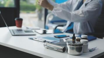A man in a lab coat sitting at a desk with a laptop video