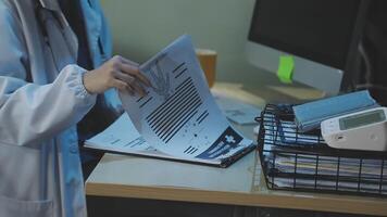 A doctor is working on paperwork in front of a computer video