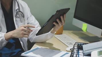 A doctor is using a tablet computer at his desk video