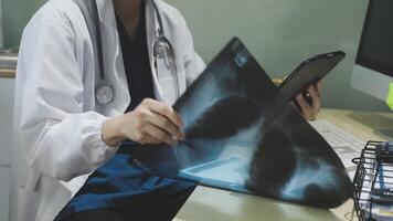A doctor is looking at an x - ray image on a tablet video