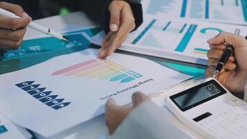 Business people working on a document with graphs and calculators video