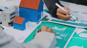 A person is working on a paper with a house and a model video
