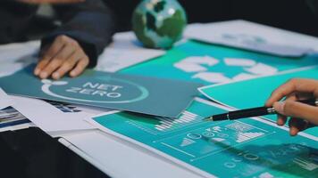 People working on a table with papers and a net zero logo video