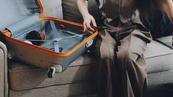 une femme séance sur une canapé avec un ouvert valise video