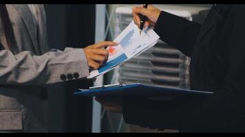 Two people are holding papers and one is looking at a clipboard video
