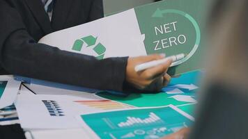 A man in a suit holding a net zero sign video
