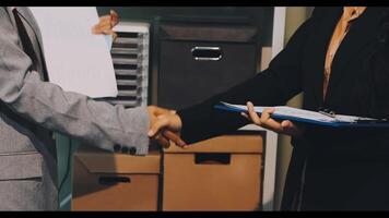 Two people shaking hands in front of a desk video
