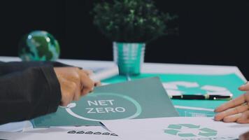 Two people sitting at a table with a net zero logo video