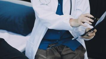 A doctor is holding a clipboard while sitting on a bed video