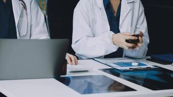 Two doctors sitting at a table with a laptop video