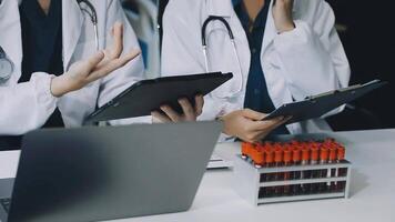 Two doctors are working on a laptop and tablet video