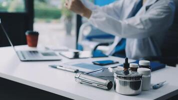 A man in a lab coat sitting at a desk with a laptop video