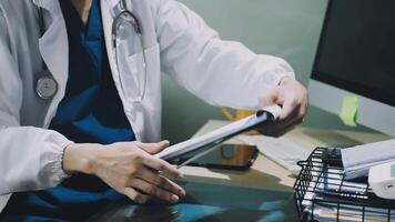 A doctor is working on a computer while holding a clipboard video