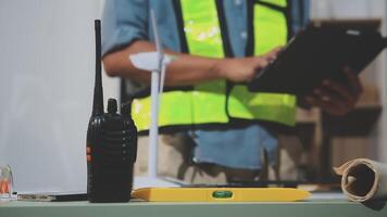 A man in a safety vest holding a tablet computer and a walkie talkie video