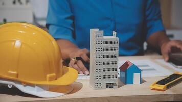 A person working on a construction project with a hardhat and a model of a building video