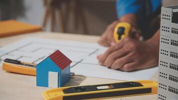 uma pessoa é trabalhando em uma projeto com uma casa e uma ferramenta video