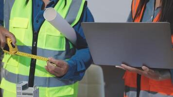 Two construction workers are holding a laptop and measuring tape video