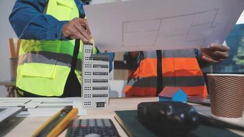 Two construction workers are working on a model of a building video