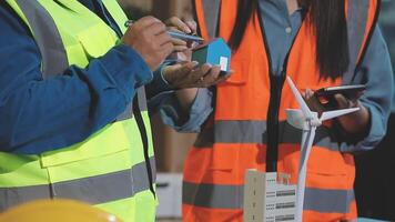 Two people in safety vests holding a wind turbine video