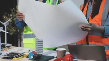 Two people in safety vests holding a paper with wind turbines video